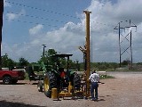 The Model 80 fence post driver getting hooked up to a John Deere Tractor.